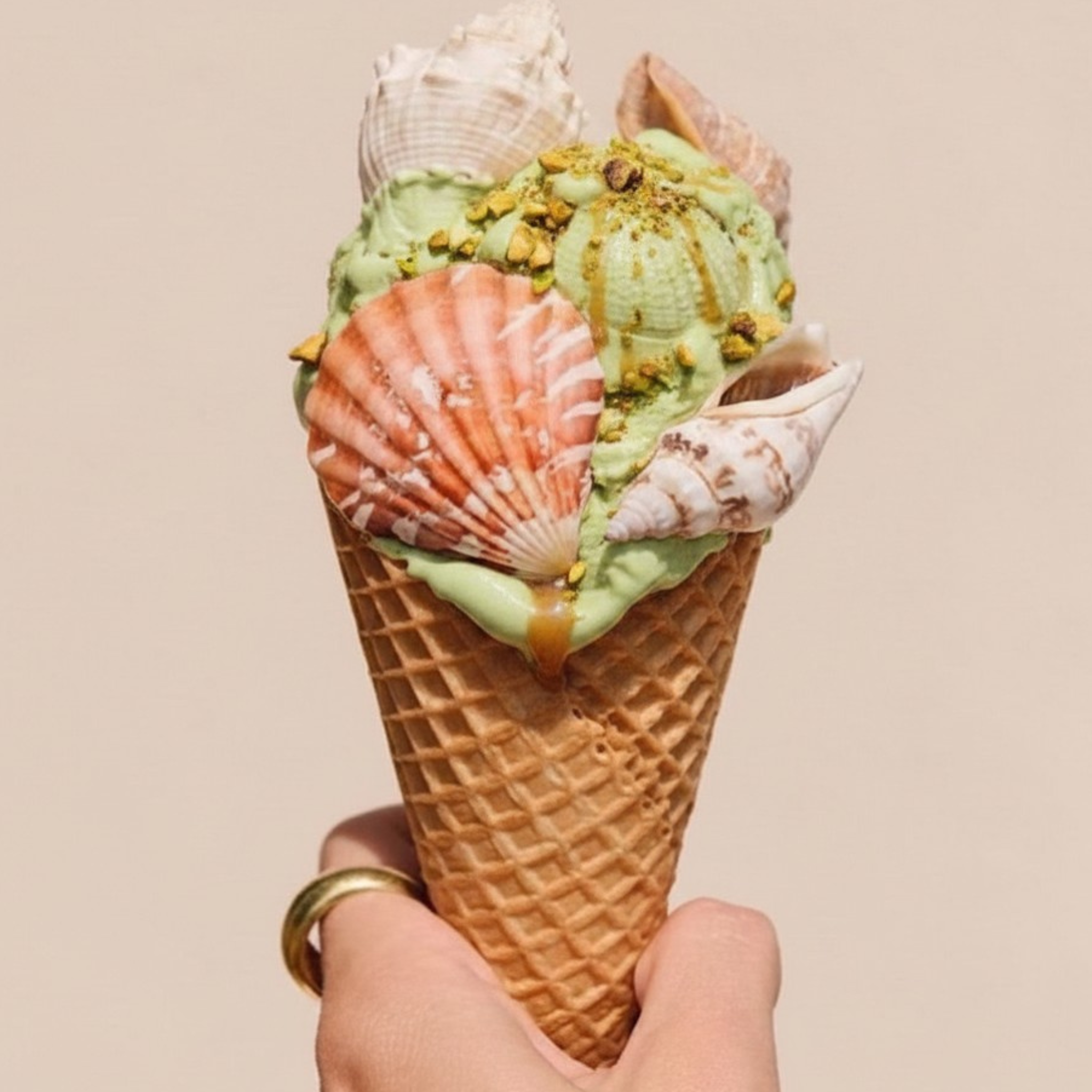 Pistachio ice cream mixed with seashells, pistachio nuts, and drizzled with caramel in a waffle cone.