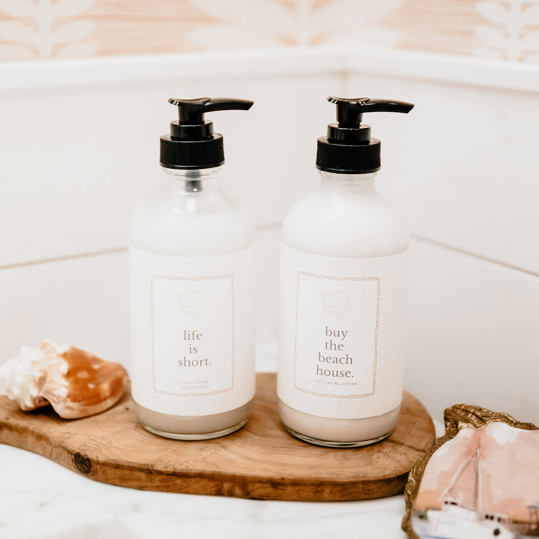 Two bottles with pump dispensers on a wooden tray in a bathroom setting.